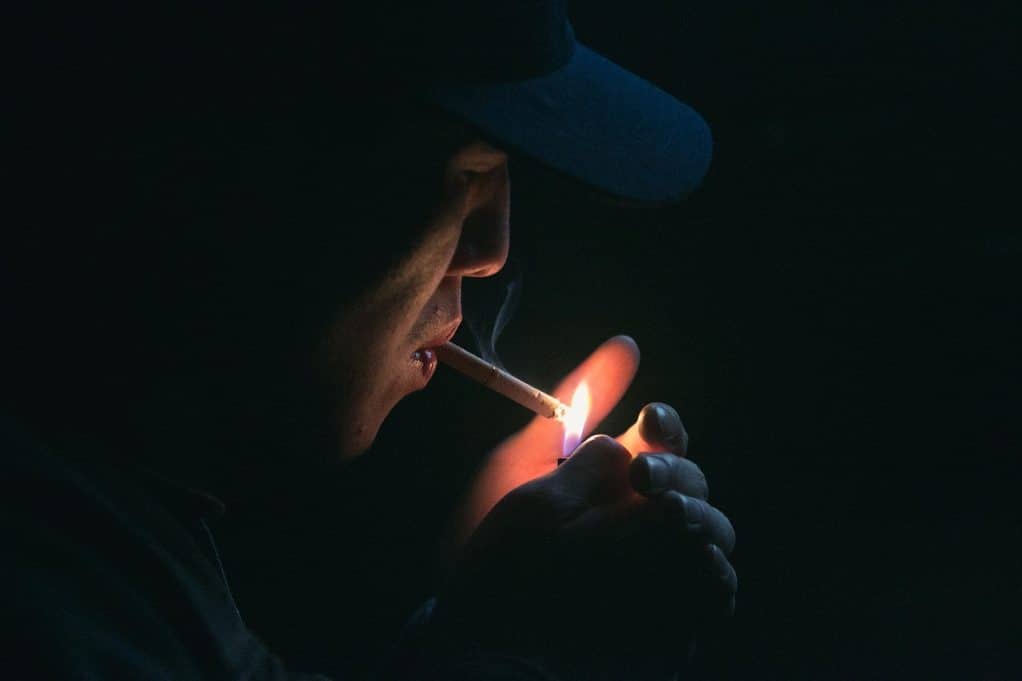 אדם מעשן סיגריה בחושך